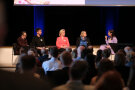Fünf Personen sitzen in einer Diskussionsrunde auf der Bühne.